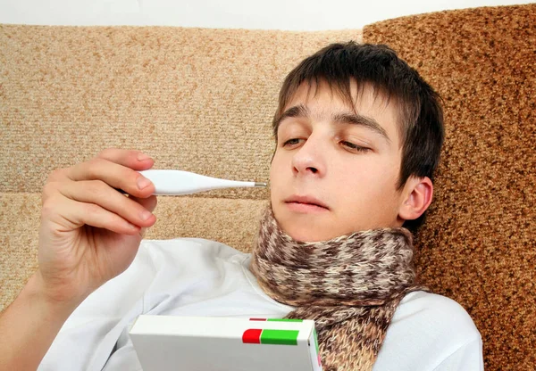 Junger Mann Mit Medizinischem Thermometer Auf Dem Heimischen Sofa — Stockfoto