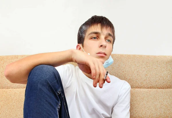 Hombre Joven Con Una Máscara Gripe Está Fumando Cigarrillo Sofá — Foto de Stock