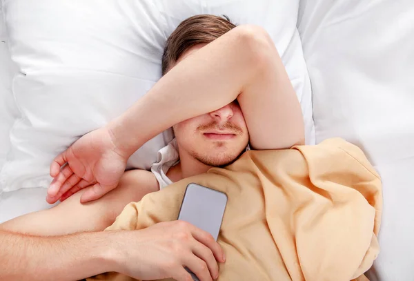 Trött Ung Man Sover Sängen Med Mobiltelefon — Stockfoto