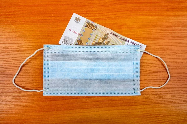 Protective Medical Flu Mask and Russian Rubles on the Wooden Table closeup