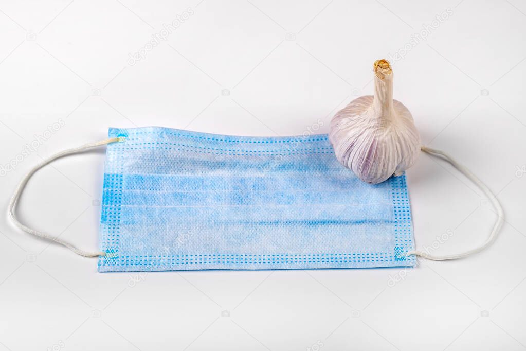 Protective Medical Flu Mask and Garlic on the White Background closeup