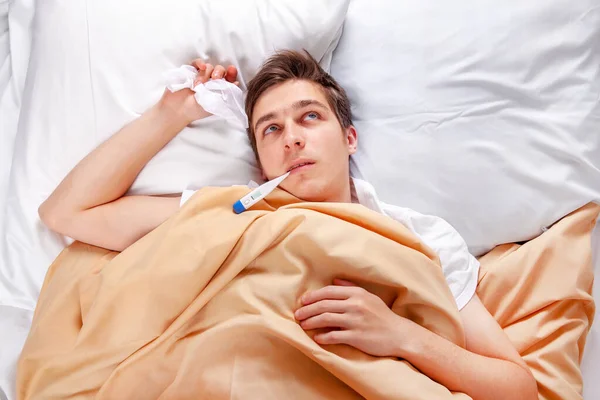 Sjukt Ung Man Med Termometer Sängen Hemma — Stockfoto