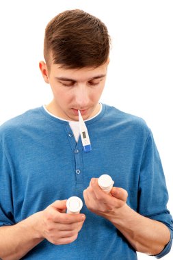 Termometresi olan genç adam beyaz arka planda izole edilmiş bir ilaç tutuyor.