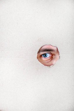 Erkek Gözü, kartondaki delikten gizlice bakıyor.
