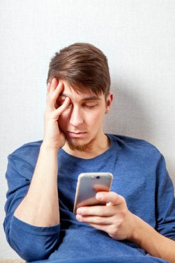 Evinin duvarında telefonu olan üzgün genç adam.
