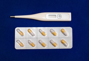 Mavi kumaş arka planında termometresi olan haplar.