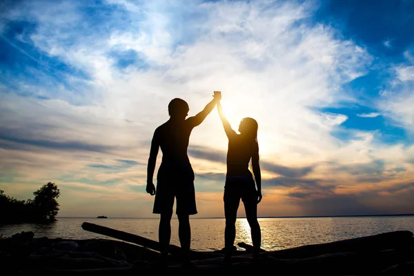 夕日を背景に手を挙げて幸せなカップルシルエット — ストック写真