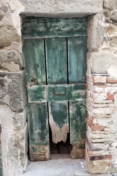 Puerta de madera vieja andrajosa en una pared de piedra. Italia Lago de Garda. Entrada a una casa en el pueblo . — Foto de Stock