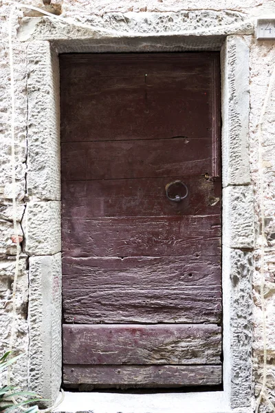 Puerta de madera marrón en una pared de piedra primer plano de la casa de pueblo. Italia  . — Foto de Stock