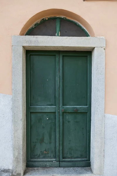 Green door with bronze handles in the stone wall background. pointed style — Stock Photo, Image