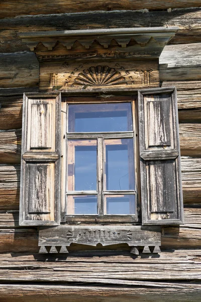 Janela velha com vidro com um céu azul no fundo da parede de madeira da casa de madeira . — Fotografia de Stock