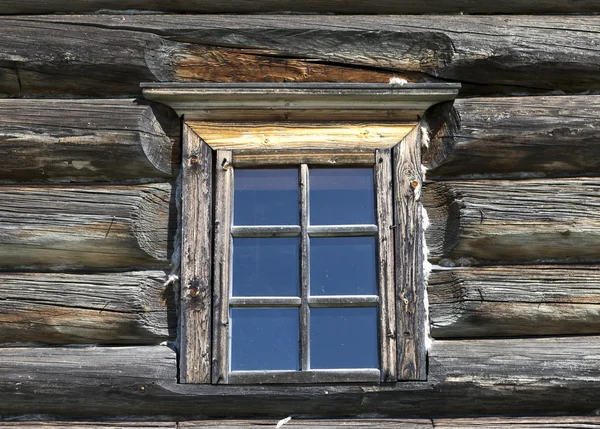 Kleine oude venster met glas met een blauwe lucht op de achtergrond van de houten muur van het platteland blokhuis — Stockfoto