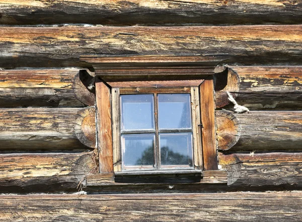 Janela velha pequena com vidro com um céu azul no fundo da parede de madeira da casa de madeira do campo — Fotografia de Stock
