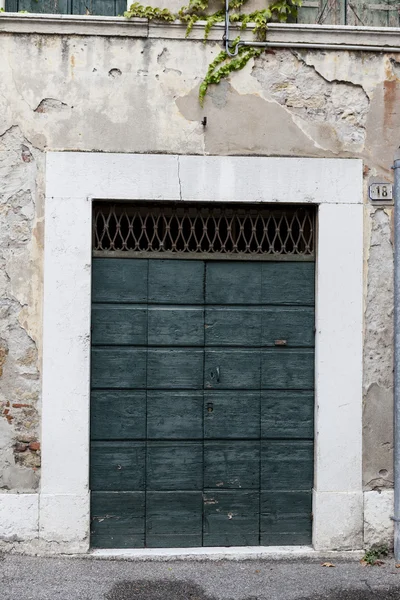 Green door with bronze handles in the stone wall background. — Stock Photo, Image