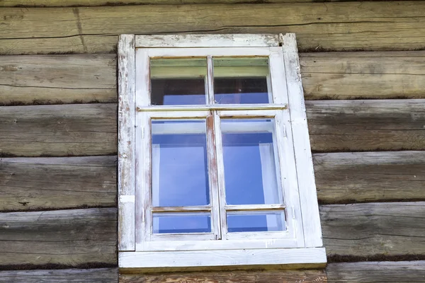 Janela velha com vidro com um céu azul no fundo da parede de madeira da casa de madeira do campo — Fotografia de Stock