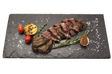 Striploin biftek pişmiş patates ve barbekü sosu bir taş plaka üzerinde ızgara.