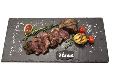 Striploin biftek pişmiş patates ve barbekü sosu bir taş plaka üzerinde ızgara.