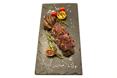 Striploin biftek pişmiş patates ve barbekü sosu bir taş plaka üzerinde ızgara.