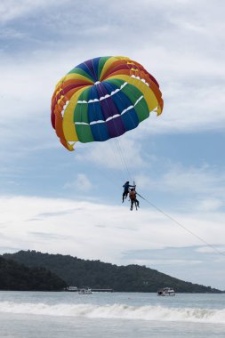 Güzel renk büyük paraşüt mavi gökyüzü tropikal Beach. Phuket Tayland bir plajda denize bir paraşüt üzerinde uçan iki Çinli turistler.