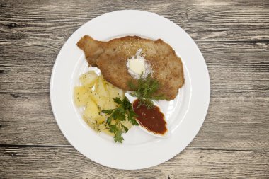 Tereyağı, haşlanmış patates ve baharatlı domates sosu ile sulu Wiener schnitzel. Avusturya Ulusal çanak Wiener schnitzel ile beyaz tabak.