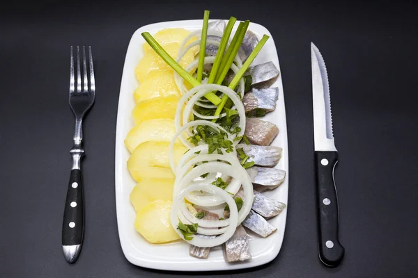 Ολλανδικό εθνικό ορεκτικό, ρέγγα με κρεμμύδι. Νόστιμα κομμάτια της Ισλανδικής ρέγγα με βραστές πατάτες και κρεμμύδια στο πιάτο. — Φωτογραφία Αρχείου