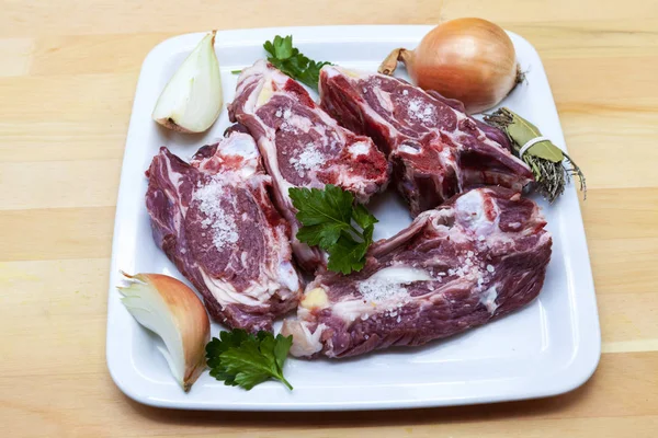 Pedaços de cordeiro fresco no prato. Delicioso cordeiro de cauda gorda com cebola no prato. Carne a grelhar . — Fotografia de Stock