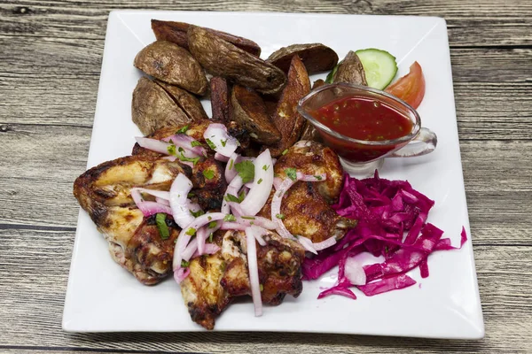Жареные куриные крылышки на тарелке с острым луком и красной капустой и картошкой Айдахо . — стоковое фото