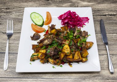 Patates ve salatalık ve domates plaka üzerinde kırmızı lahana ile Kızartma domuz