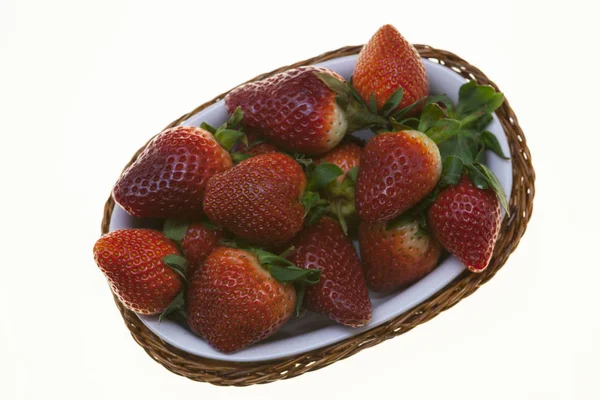 Сочные ягоды спелой клубники в плетеной корзине на белом фоне . — стоковое фото
