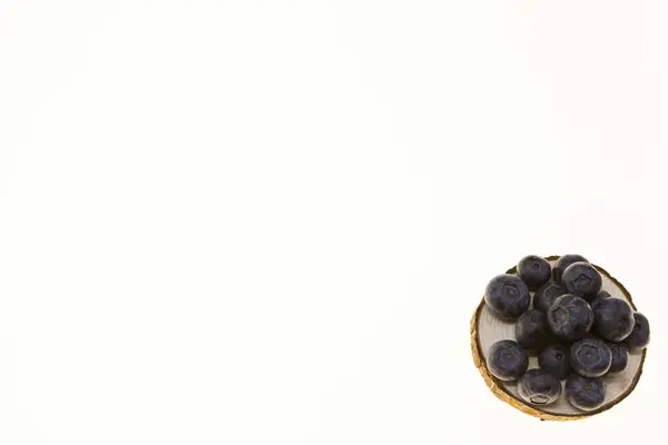 Arándanos en un plato de madera sobre un fondo blanco closeup.Background para la confitería, café bayas frescas para pasteles . — Foto de Stock