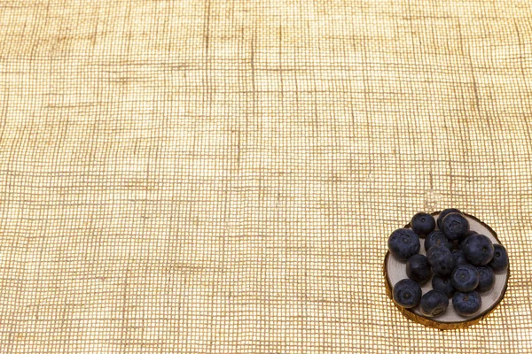 Los arándanos en un plato de madera sobre un fondo de lino closeup.Background para la confitería, café bayas frescas para pasteles . — Foto de Stock