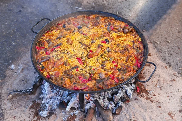 Paella. Il piatto nazionale spagnolo di paella in una padella grande è cucinato su un fuoco aperto, sul rogo . — Foto Stock