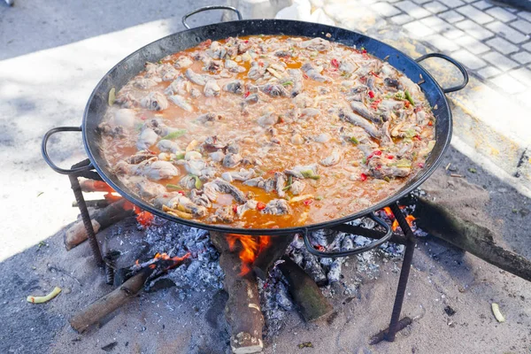 Paella. Il piatto nazionale spagnolo di paella in una padella grande è cucinato su un fuoco aperto, sul rogo . — Foto Stock