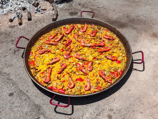 Паэлья из морепродуктов. Национальное испанское блюдо паэльи в большой сковороде готовится на открытом огне, на костре . — стоковое фото