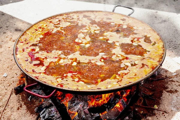 Paella ai frutti di mare. Il piatto nazionale spagnolo di paella in una padella grande è cucinato su un fuoco aperto, sul rogo . — Foto Stock