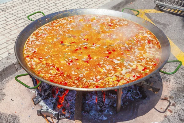 Paella di pollo, verdure e riso. Il piatto nazionale spagnolo di paella in una padella grande è cucinato su un fuoco aperto, sul rogo . — Foto Stock