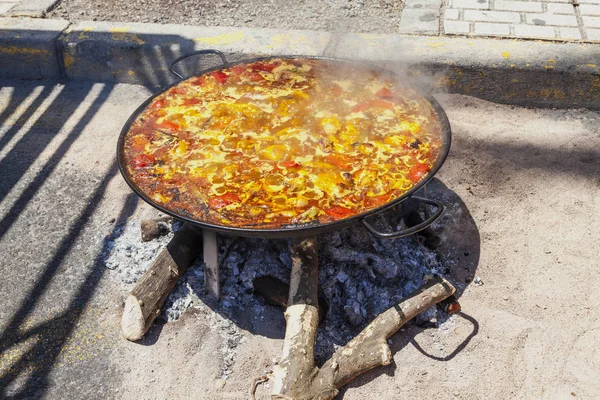 Paella di pollo, verdure e riso. Il piatto nazionale spagnolo di paella in una padella grande è cucinato su un fuoco aperto, sul rogo . — Foto Stock