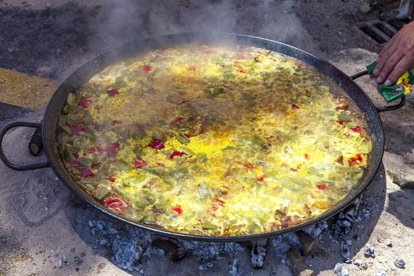 Paella di pollo, verdure e riso. Il piatto nazionale spagnolo di paella in una padella grande è cucinato su un fuoco aperto, sul rogo . — Foto Stock