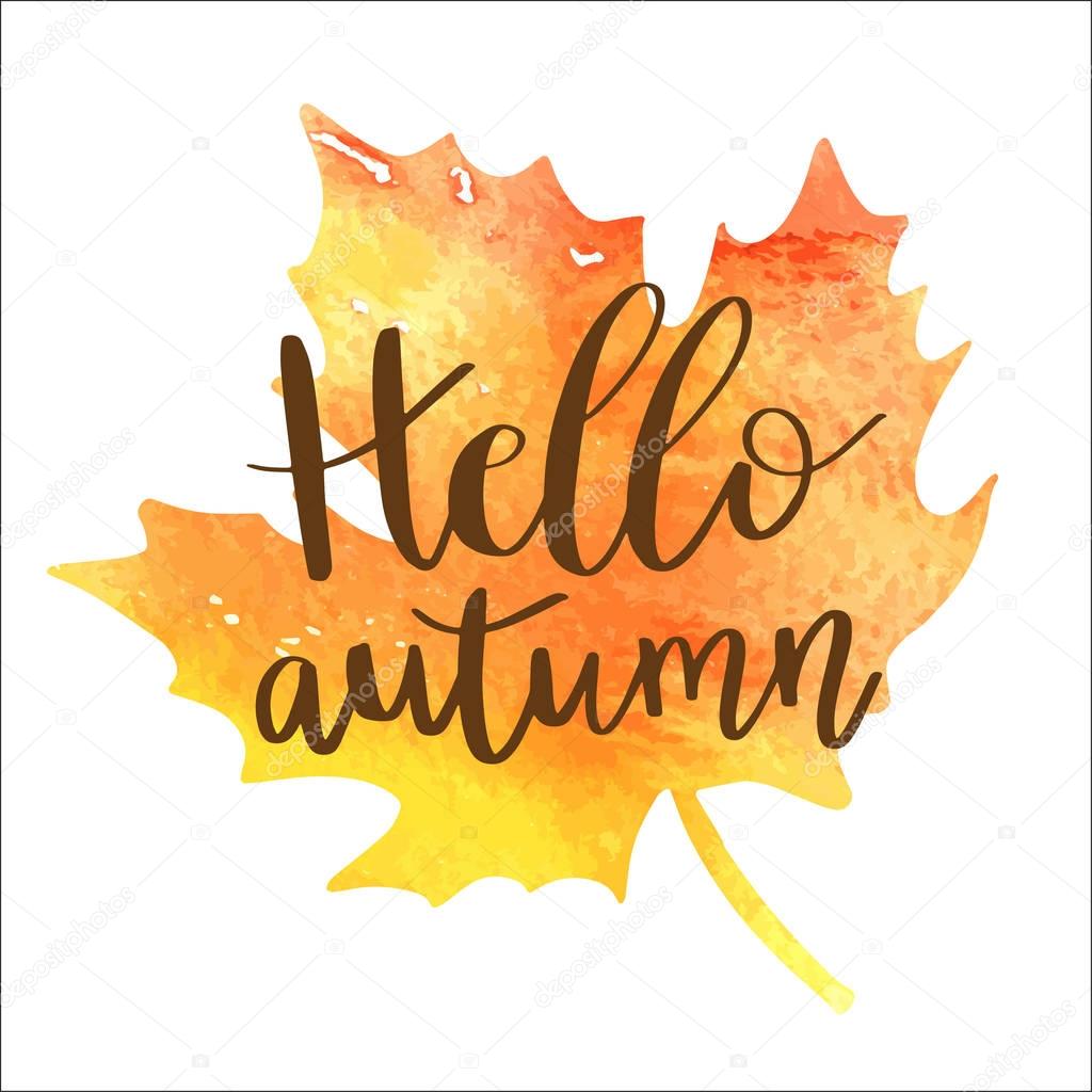 Hello autumn hand lettering phrase on orange watercolor maple leaf background.