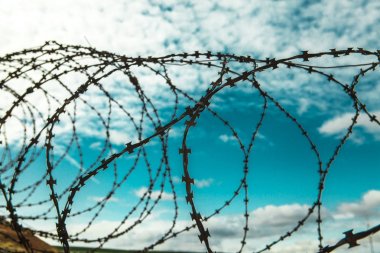 Dikenli tel. Mavi gökyüzü arka plan beyaz bulutlar ile üzerinde dikenli tel. Tel boom. Askeri çatışma. Suriye.