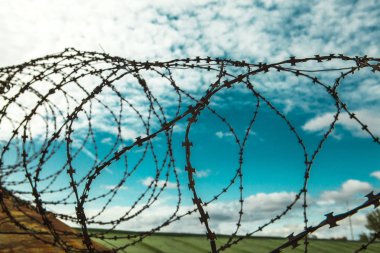 Dikenli tel. Mavi gökyüzü arka plan beyaz bulutlar ile üzerinde dikenli tel. Tel boom. Askeri çatışma. Suriye.