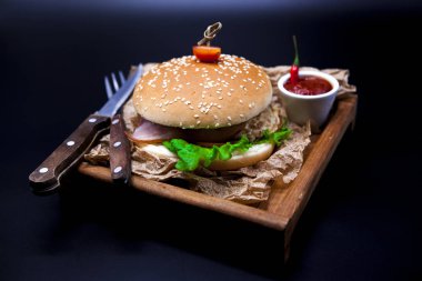 Sulu hamburger. Mermer sığır eti, çatal bıçak ve chili sos gazetesi ile Burger