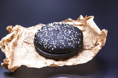 Bun siyah bir hamburger için. Kağıt üzerine susam ile siyah bir topuz.