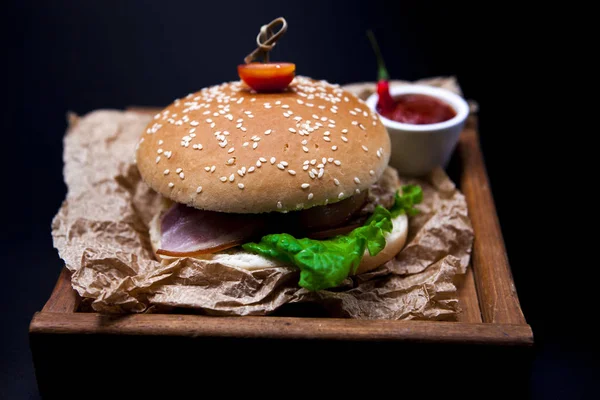 Um hambúrguer suculento. Hambúrguer com carne de mármore, garfo com faca e molho de pimenta no jornal — Fotografia de Stock