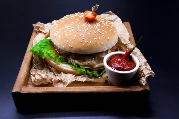 Een sappige hamburger. Hamburger met marmeren rundvlees, voorvork met mes en chili saus — Stockfoto