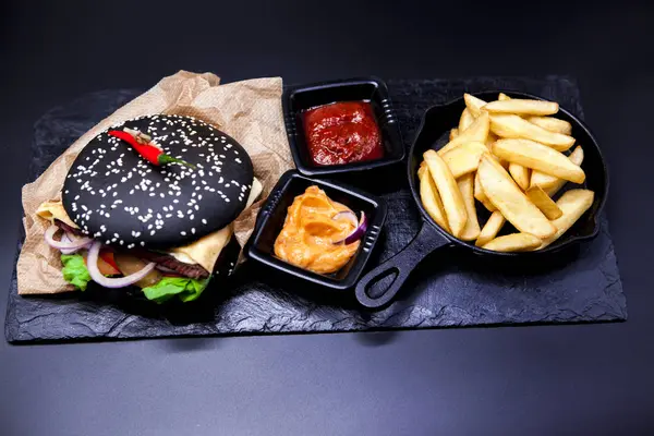 Leckeres Set: Burger, Pommes, Currysoße, Chilisoße, Gabel und Messer. — Stockfoto