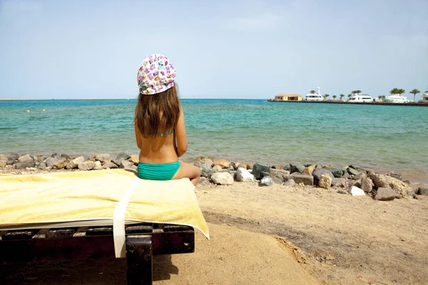 Menina está sentada na praia — Fotografia de Stock
