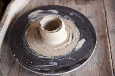 Çamurlu Potter tekerleği. Kadın eli kilden bir vazo yapar.