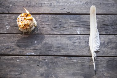 Yanan bir mumla yazmak için tüy. Tüy yanan bir mumla eski bir ahşap masanın üzerinde yatıyor. Peçeteler, duvar kağıtları, kitaplar, defterler, kâğıtlar için harika bir arka plan. Retro biçimi, eski zaman