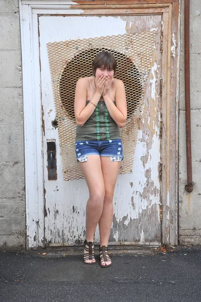 Kadın güzelliğinin ifadeleri bir grunge kapının dışında karşı.